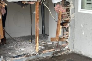 Front wall of a house broken open with snapped studs after a car crashed into it