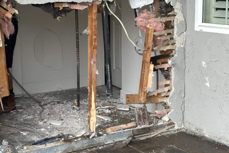Front wall of a house broken open with snapped studs after a car crashed into it