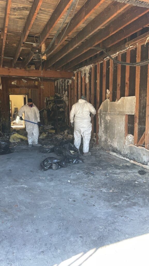 Crew in protective suits removing debris during garage fire cleanup