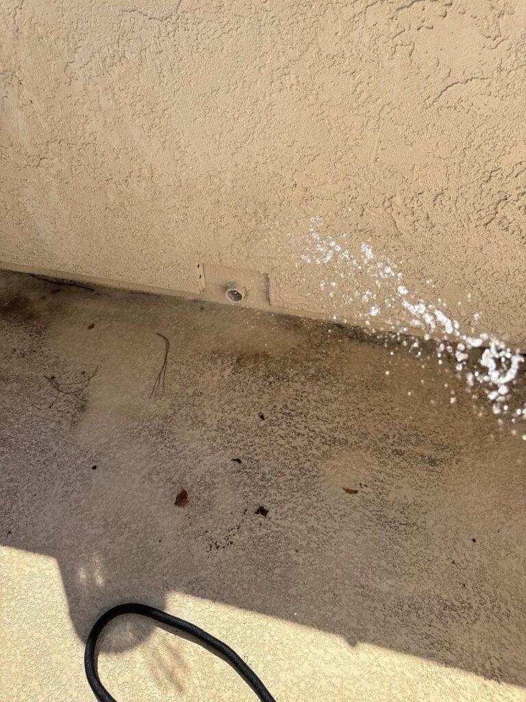 Water test with a hose along the base of a deck wall during leak detection