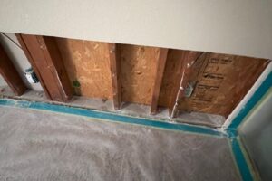 Mold behind drywall inspection: bedroom drywall cut along the bottom of the wall to expose the framing