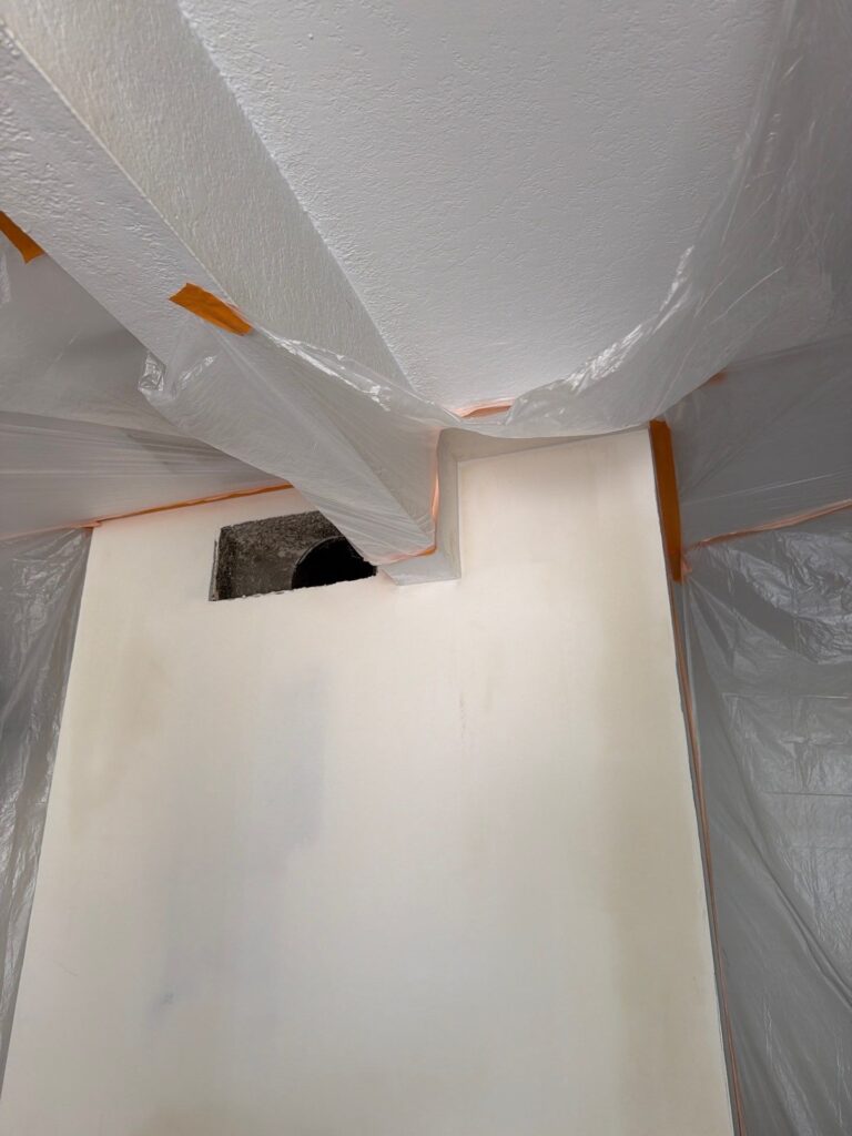 Plastic sheeting taped around a wall opening during drywall repair after a repipe