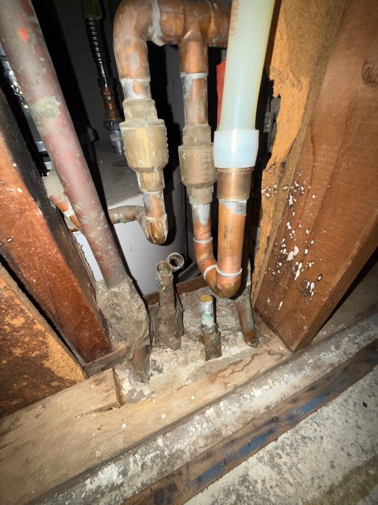 Open wall cavity showing copper pipe and new water line during a repipe