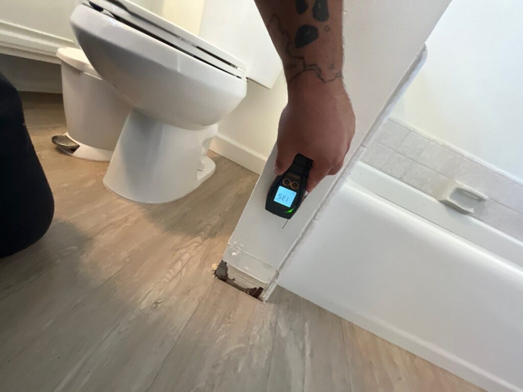Moisture meter reading at the base of a bathtub after a sewage backup