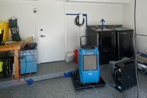 Dehumidifier drying a garage laundry wall after a washing machine leak