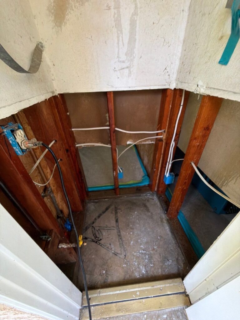 Water heater closet with the heater removed and drywall cut back to the framing