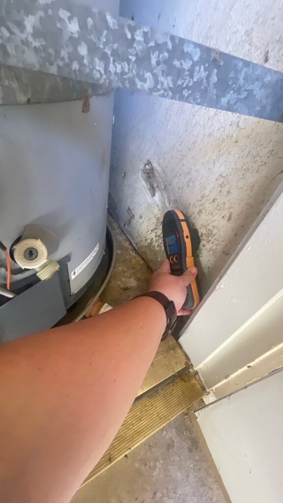 Moisture meter reading on the closet wall next to a leaking water heater